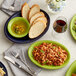 An Acopa Capri bamboo stoneware fruit bowl on a table with a plate of macaroni and cheese.