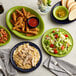 A table with Acopa Capri green stoneware plates of food, salad, and bread with a bowl of soup.