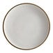 An Acopa Keystone Vanilla Bean stoneware coupe plate with brown specks on the edges.