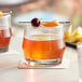 Two Acopa Saloon rocks glasses with cocktails garnished with fruit.