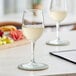 Two Acopa Select Flora wine glasses filled with white wine on a table