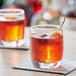 An Acopa rocks glass filled with whiskey and an orange slice on top.