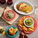 A table with Acopa Capri Caribbean Turquoise stoneware plates of food, including tacos and guacamole.