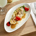 A white Acopa Nova triangle stoneware plate with food on it.