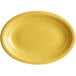 A citrus yellow oval stoneware platter with a rim on a white background.