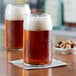 Two Acopa Select can glasses of beer on a table.