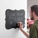 A man writing on a Choice decorative chalkboard label.