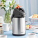 An Acopa stainless steel decaf airpot on a table.