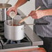 A person pouring milk into a Choice aluminum sauce pan.