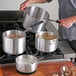 A man cooking soup in a Choice aluminum sauce pan on a stove.