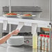 A Choice aluminum wall mounted ticket holder on a counter in a professional kitchen.