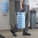 A man in a chef's outfit holding a large blue Vollrath Traex ice bucket.