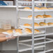 A woman wearing gloves holding a Winholt polystyrene display tray of bread.