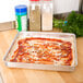 An American Metalcraft aluminum pizza pan holding a pizza on a counter.