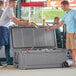 Two men opening a CaterGator mobile outdoor cooler with a gray lid.