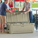 Two men standing next to a tan CaterGator outdoor cooler with the lid open to reveal cans.
