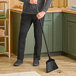 A person holding a Libman commercial angle broom and sweeping the floor in a professional kitchen.