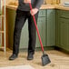 A person using a Libman commercial angle broom to sweep the floor in a professional kitchen.