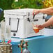 A person pouring a drink from a tap into a plastic cup.