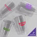 A group of clear plastic Choice highball glasses. One has a pink logo and one has a purple logo.
