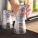 A person holding a stack of clear plastic Choice Rocks glasses.