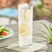 A Choice SAN plastic Tom Collins glass of lemonade with ice and lemon slices on a napkin.