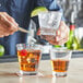 A man holding an Acopa Select flared rocks glass with a drink and a lime wedge.