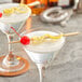 A pair of martini glasses with a cherry and lemon garnish using Bamboo by EcoChoice bamboo paddle skewers.