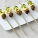 Bamboo flat skewers with meat and vegetables on a white plate.