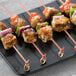 Bamboo skewers holding chicken and vegetables on a plate.