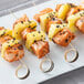Bamboo skewers with sushi and chicken on a plate.