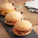 Three hamburgers on a table with Bamboo by EcoChoice trident skewers.
