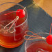 Two glasses of liquid with cherries on top, each with a red bamboo heart skewer.