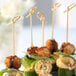 A plate with appetizers on Bamboo by EcoChoice bamboo knot food picks on a table at a catering event.