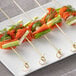 Bamboo food skewers with smoked salmon on a plate.