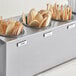 A gray stainless steel flatware organizer with wooden spoons and forks in it.