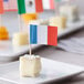 A plate of cheese with French flags on toothpicks.