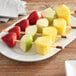A plate of fruit skewers with apples, pineapples, and strawberries.
