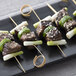 A plate with Bamboo by EcoChoice bamboo loop skewers of meat and green onions on a table.