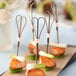 Bamboo skewers with heart-shaped ends in pieces of salmon with green onions.