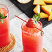 A strawberry on a Bamboo by EcoChoice red bamboo skewer in a glass of strawberry and orange juice with ice.