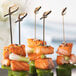 Bamboo skewers of salmon, cucumber, and celery on a table.