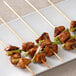 A plate with chicken and green onions on EcoChoice bamboo skewers.