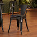A Lancaster Table & Seating black metal arm chair with a black wood seat.