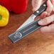 A person holding a Mercer Culinary knife with a red polypropylene blade guard.