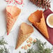 A close up of a Konery Pumpkin Spice waffle cone filled with candy on a marble surface.