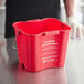 A red San Jamar sanitizing bucket with white text on a counter.
