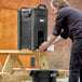 A man using a CaterGator portable handwash station to pour water into a black container.