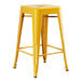 A Lancaster Table & Seating yellow metal backless counter height stool with legs.