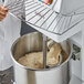 a person holding a metal rack with dough in a bowl